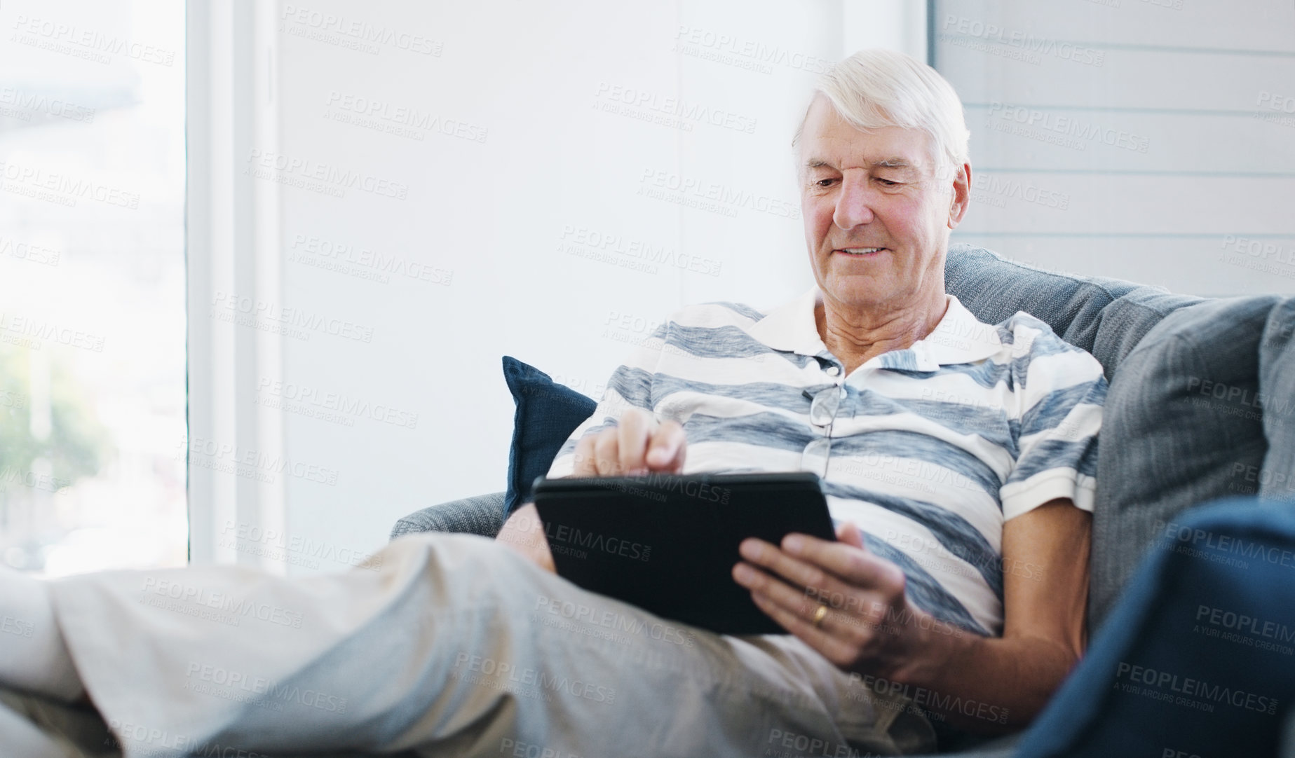 Buy stock photo Shot of a senior man using a digital tablet on the sofa at home