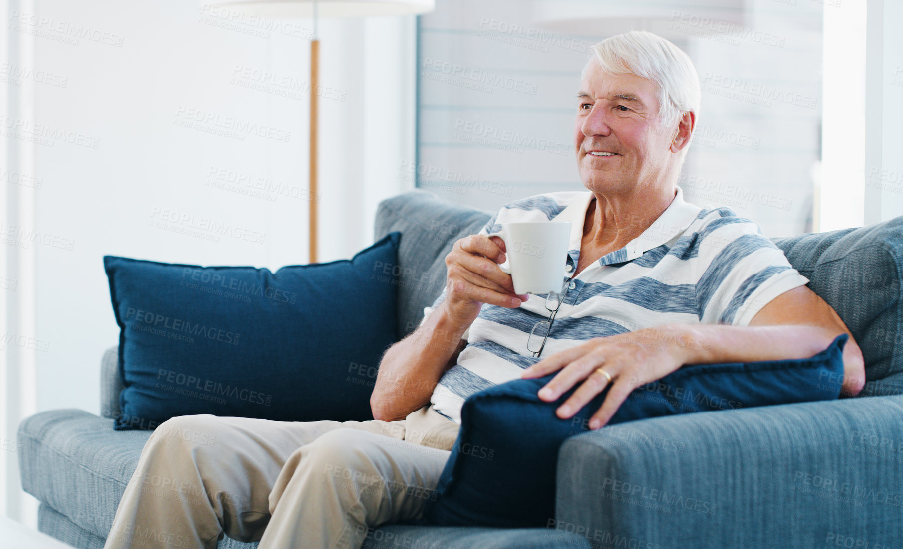 Buy stock photo Coffee, thinking and senior man on couch with morning routine, warm drink and weekend reflection for peace. Smile, resting and elderly person with tea cup in home, nostalgia and remember memory