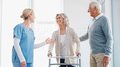 Buy stock photo Shot of a senior woman using a walker with the assistance of her husband and young nurse