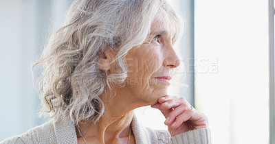 Buy stock photo Shot of a senior woman looking thoughtfully out of a window