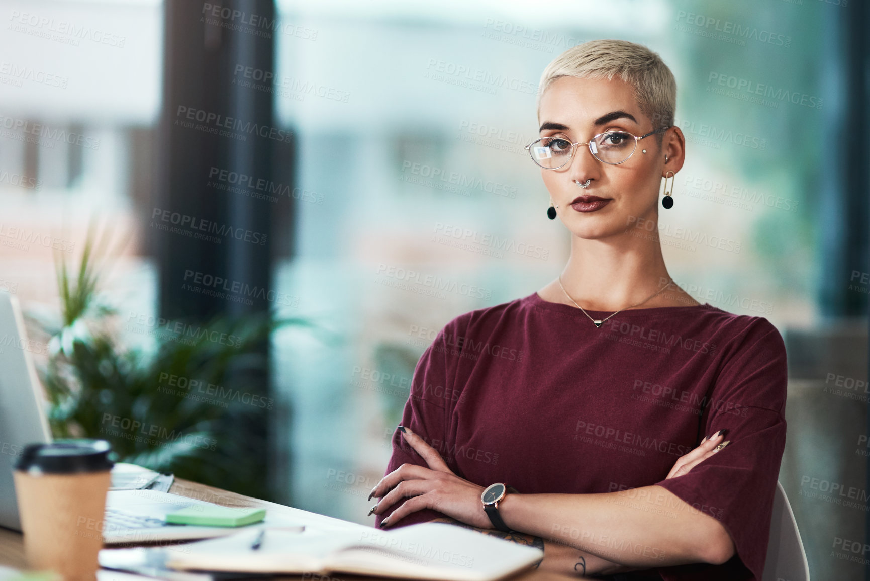Buy stock photo Cropped portrait of an attractive young businesswoman wearing spectacles and sitting alone in her office with her arms folded