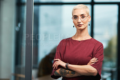 Buy stock photo Cropped portrait of an attractive young businesswoman wearing spectacles and standing alone in her office with her arms folded