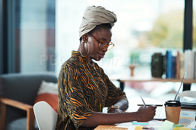 Buy stock photo Cropped shot of an attractive young businesswoman sitting alone in her office and writing notes