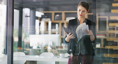 Buy stock photo Cropped shot of an attractive young businesswoman standing alone in her office and reading documents