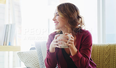 Buy stock photo Cropped shot of an attractive young woman sitting on her living room couch and enjoying a cup of coffee