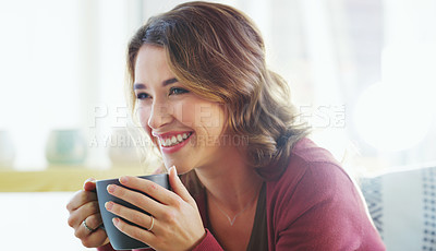 Buy stock photo Cropped shot of an attractive young woman sitting on her living room couch and holding a cup of coffee