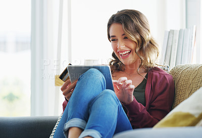 Buy stock photo Cropped shot of an attractive young woman sitting on her sofa and using her tablet for online shopping