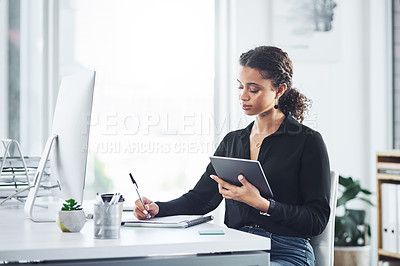 Buy stock photo Shot of a young businesswoman writing notes while using a digital tablet in an office