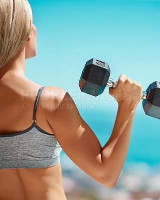 Buy stock photo Rearview shot of an unrecognizable young woman exercising with dumbbells outside