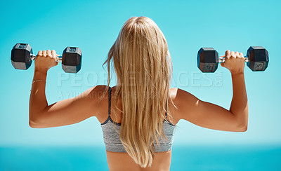Buy stock photo Rearview shot of an unrecognizable young woman exercising with dumbbells outside