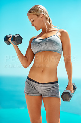 Buy stock photo Cropped shot of a beautiful young woman working out with dumbbells outside