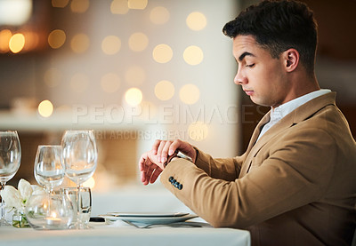 Buy stock photo Time check, watch and late date of a man at a restaurant table on valentines day alone. Bokeh lights, night and suit of a person waiting for dinner and looking at his smartwatch on anniversary