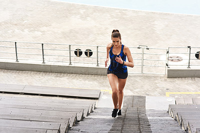 Buy stock photo Full length shot of an attractive young female athlete working out on a flight of stairs at the track