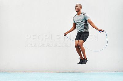 Buy stock photo Jump, rope and space with black man skipping in stadium for sports, workout and cardio. Performance, health and body with male athlete training on track for strong, mockup and exercise by wall