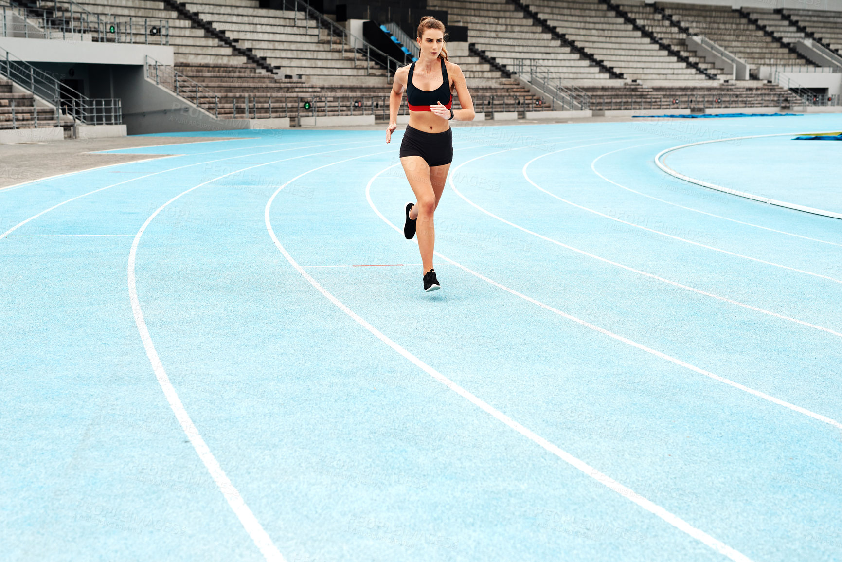 Buy stock photo Full length shot of an attractive young athlete running a track field alone during a workout session outdoors