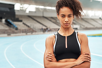 Buy stock photo Cropped portrait of an attractive young athlete standing alone with her arms folded before running a track field