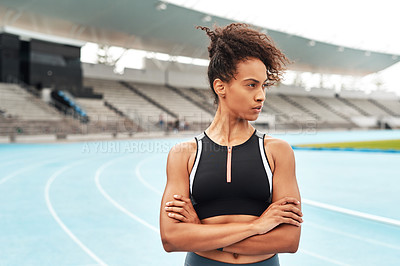Buy stock photo Cropped shot of an attractive young athlete standing alone with her arms folded before running a track field