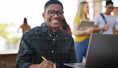 Buy stock photo Portrait of a cheerful young student working on his laptop while waiting to go to class outside of a school