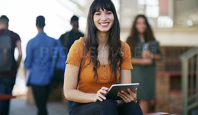 Buy stock photo Portrait of a cheerful young student browsing on her digital tablet while waiting to go to class outside of a school during the day