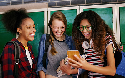 Buy stock photo Cropped shot of a group of young school kids browsing on a cellphone together while waiting to go to class inside of a school