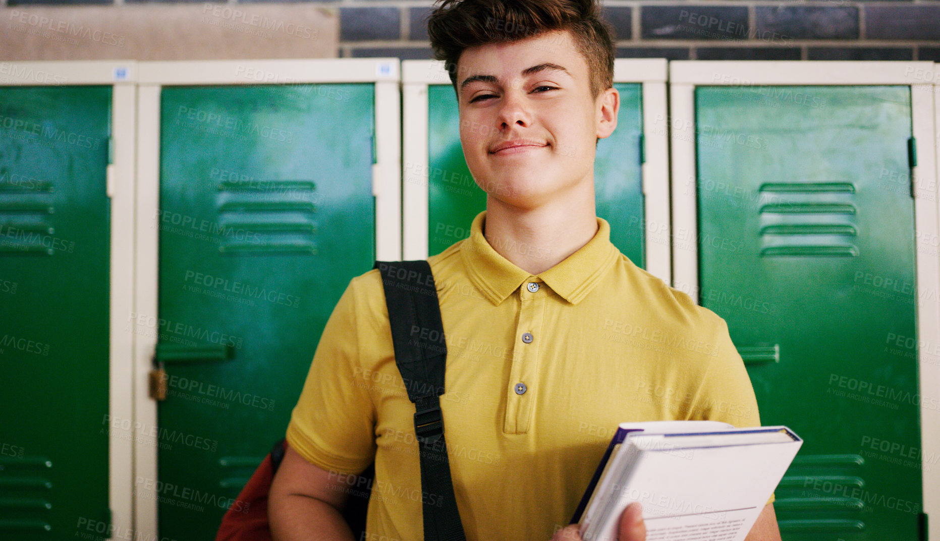 Buy stock photo Cropped shot of a cheerful young school kid holding his books while waiting to go to class inside of a school during the day