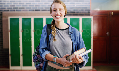 Buy stock photo Cropped shot of a cheerful young school kid holding her books while waiting to go to class inside of a school during the day