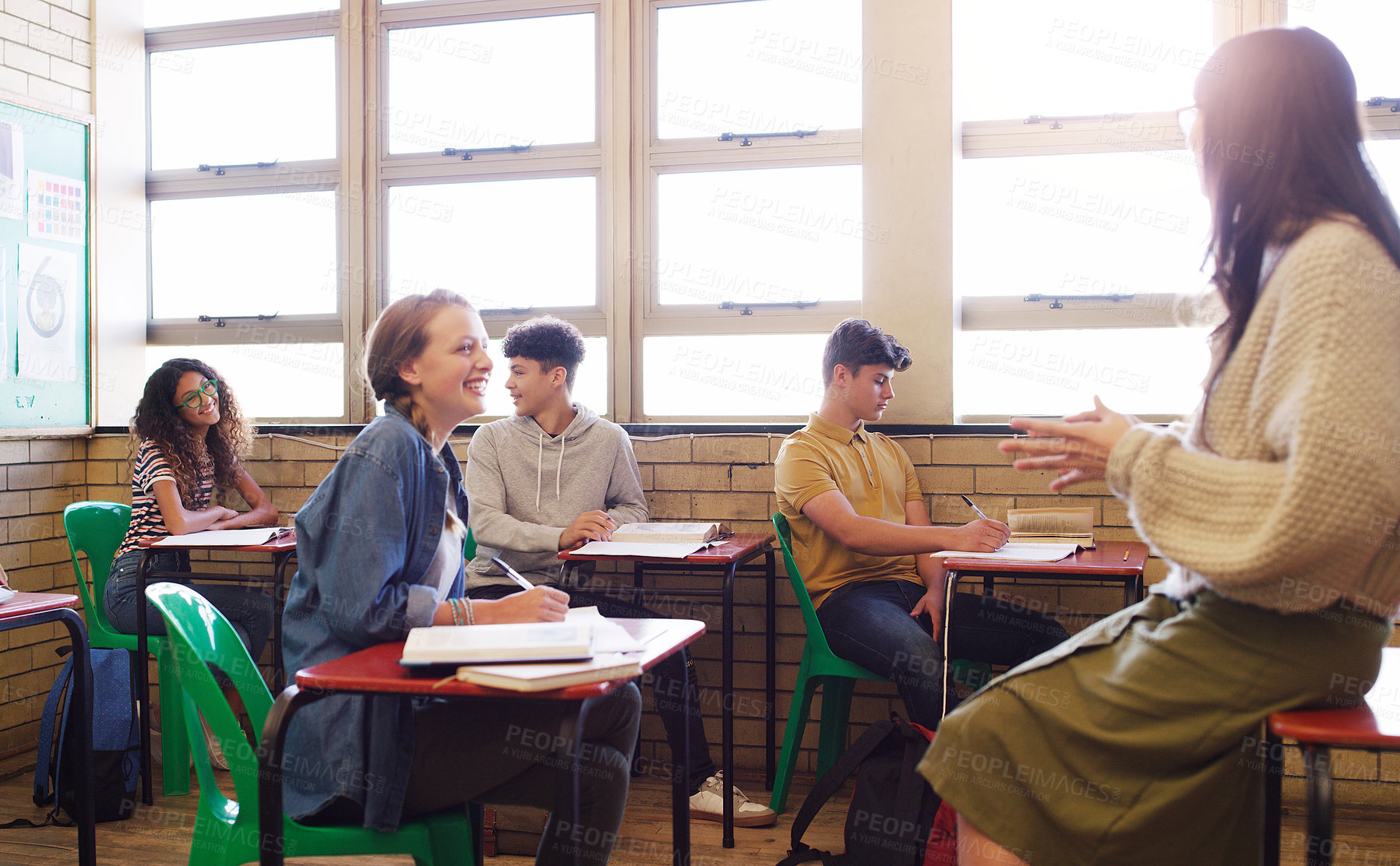 Buy stock photo Cropped shot of a cheerful young teacher giving class to a group of school kids inside of a school during the day