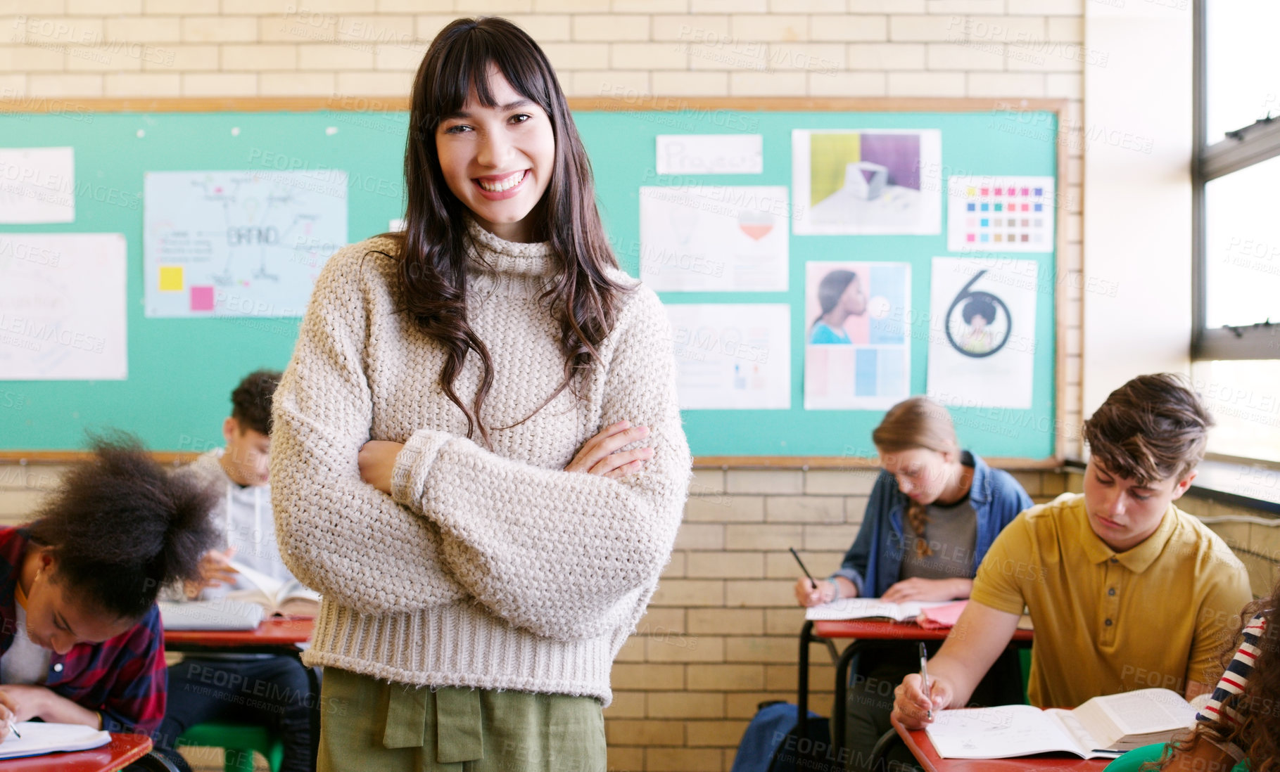 Buy stock photo Portrait of a cheerful young teacher giving class to a group of students inside of a school during the day