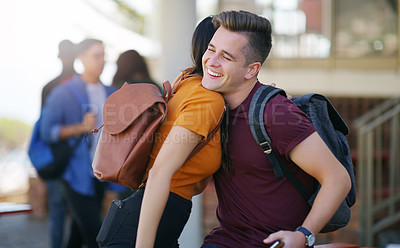Buy stock photo Cropped shot of two cheerful young students greeting each other with a hug while waiting to go to class outside of a school