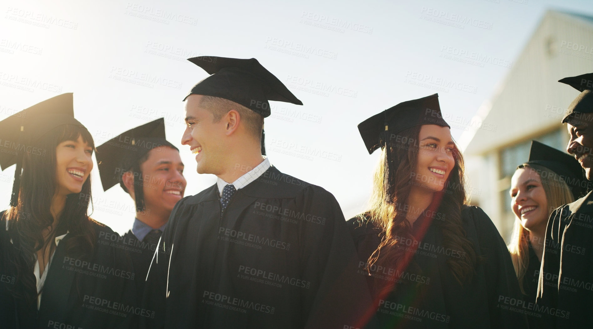 Buy stock photo Cropped shot of a group of cheerful young students standing together on graduation day outside during the day