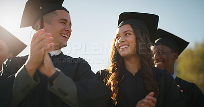 Buy stock photo Cropped shot of a group of cheerful young students standing together while clapping their hands on graduation day outside during the day