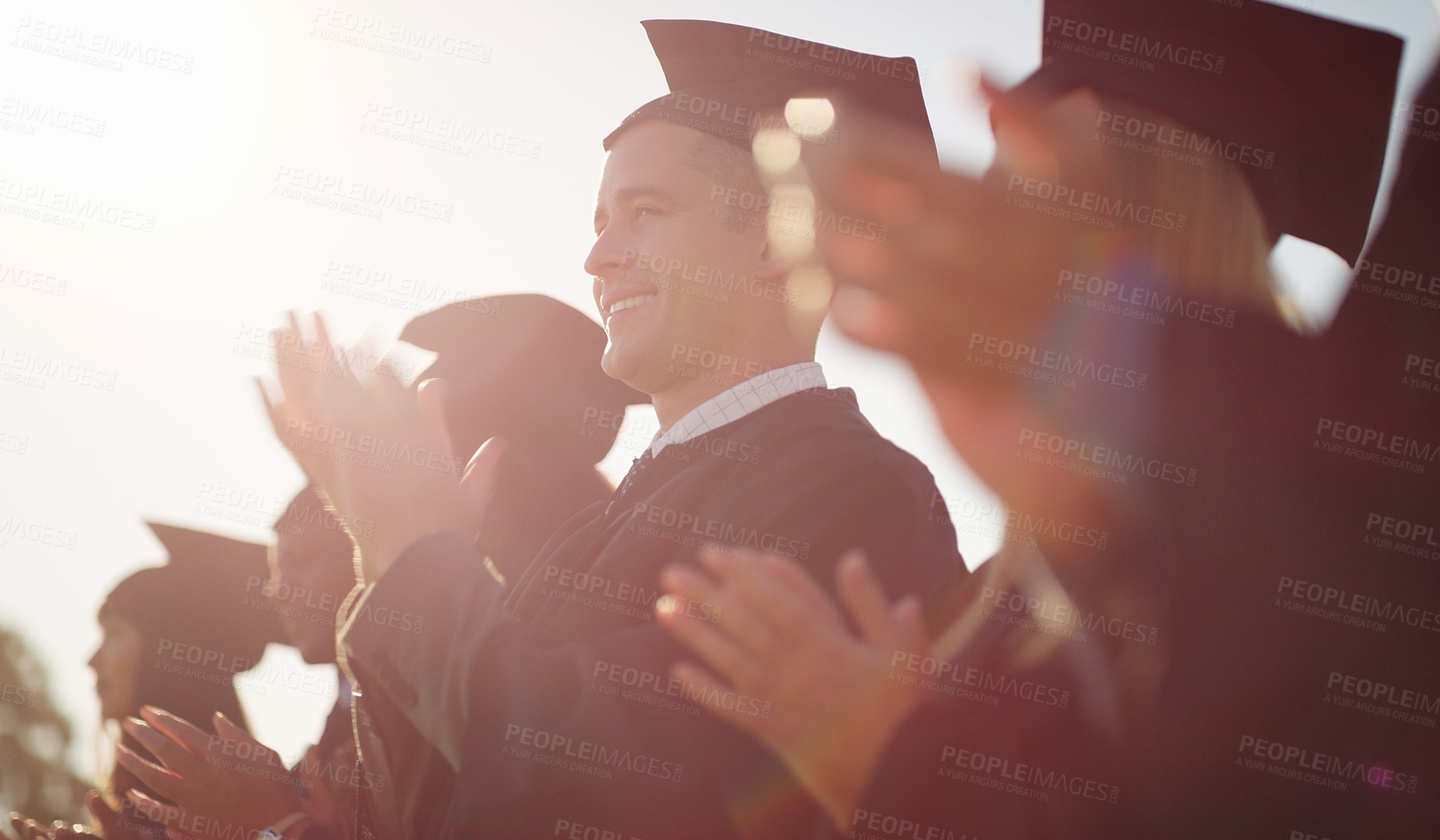 Buy stock photo Cropped shot of a group of cheerful young students standing together on graduation day outside during the day