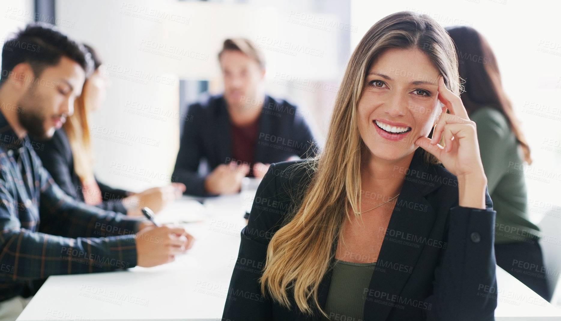 Buy stock photo Portrait of a young businesswoman sitting in an office with her colleagues in the background