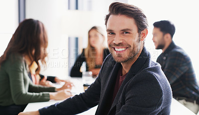 Buy stock photo Portrait of a young businessman sitting in an office with his colleagues in the background
