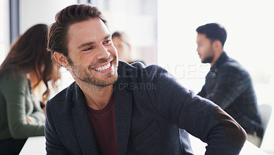Buy stock photo Shot of a young businessman sitting in an office with his colleagues in the background
