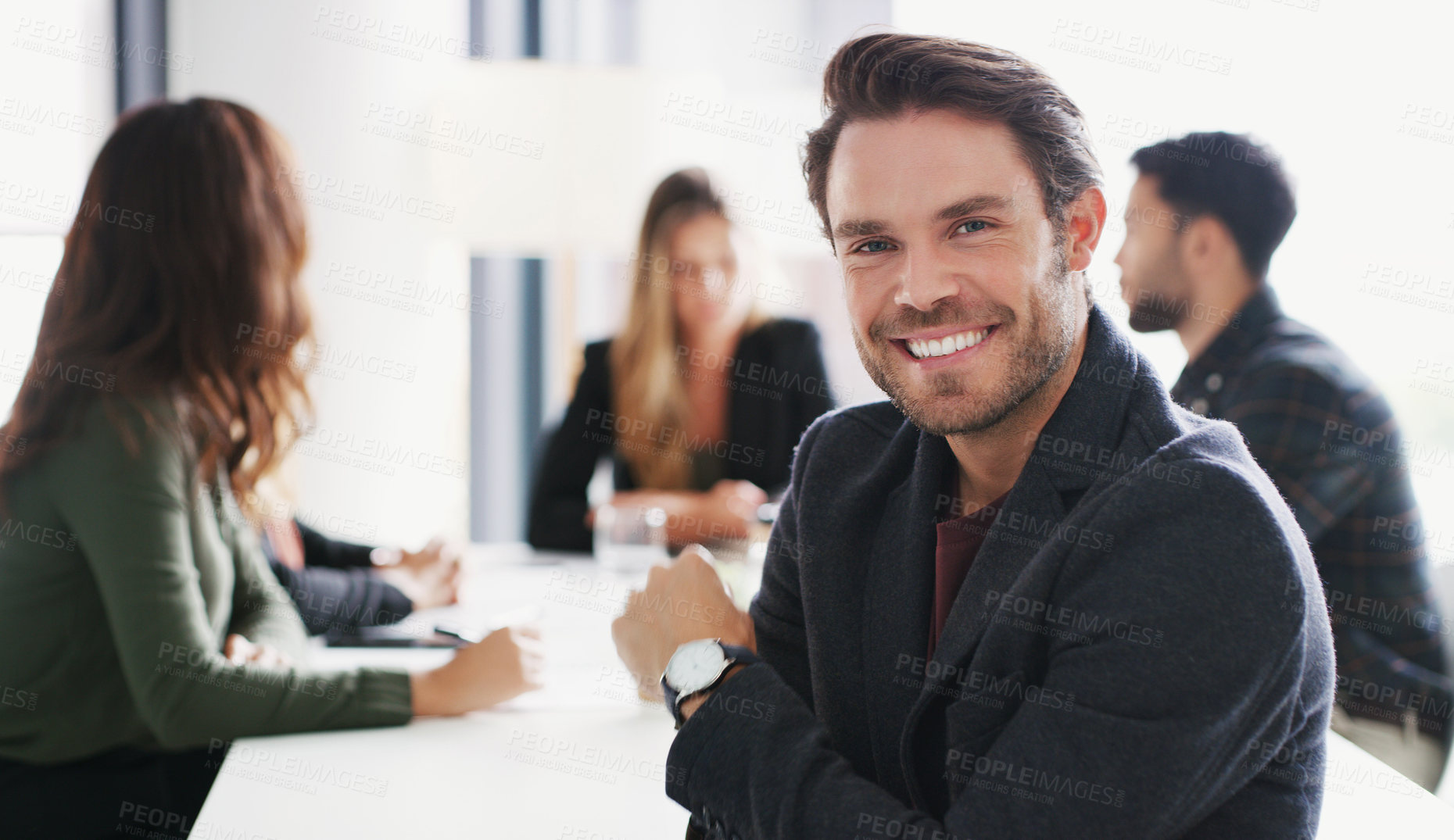 Buy stock photo Portrait of a young businessman sitting in an office with his colleagues in the background