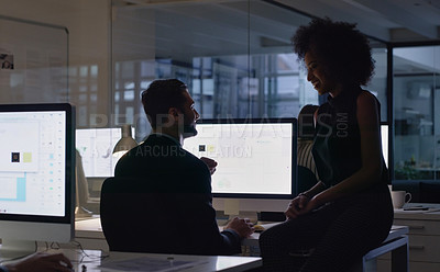 Buy stock photo Cropped shot of two young business colleagues sitting and talking with each other in the office late at night