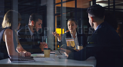 Buy stock photo Cropped shot of a diverse group of businesspeople sitting together and having a meeting in the office late at night