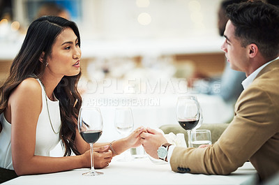 Buy stock photo Couple, wine and holding hands in restaurant with talk, love and romance for valentines day date in night. Man, asian woman and conversation for bonding, luxury fine dining and romantic celebration