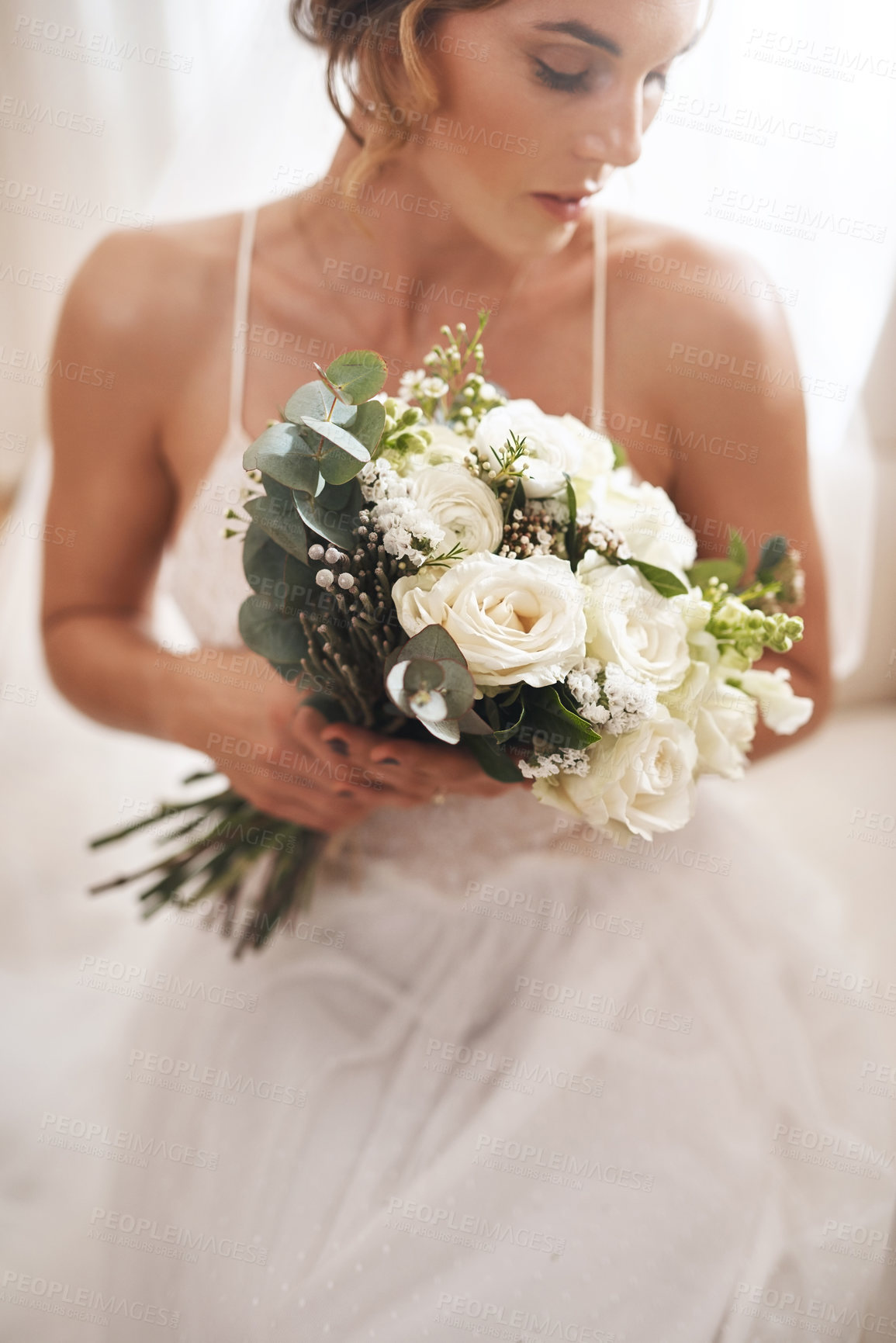 Buy stock photo Cropped shot of an attractive young bride sitting alone in the dressing room and holding her bouquet of flowers