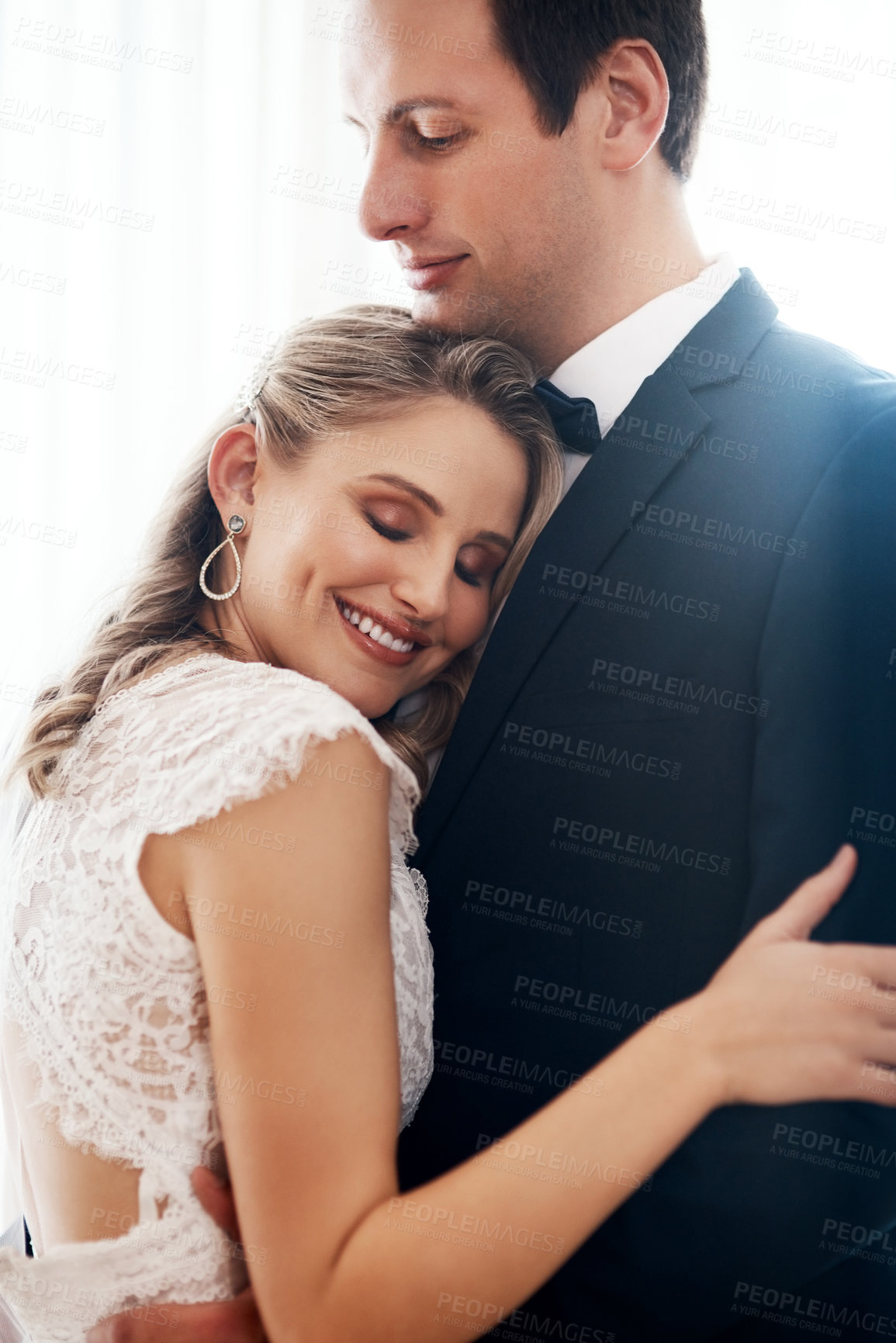 Buy stock photo Cropped shot of a happy young couple standing indoors and hugging each other affectionately after their wedding