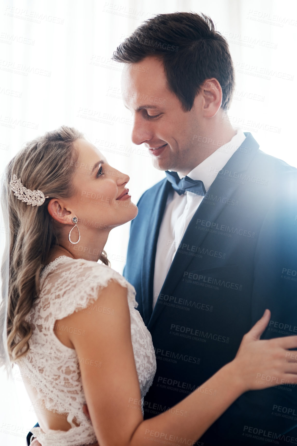 Buy stock photo Cropped shot of a happy young couple standing indoors and holding each other affectionately after their wedding
