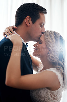 Buy stock photo Cropped shot of a handsome young groom affectionately kissing his wife on the forehead after their wedding