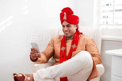 Buy stock photo Indian, wedding and groom with culture, phone and communication in ceremony, fitting or bedroom. Turban, traditional and man with smile for clothes, fashion and mobile in marriage of person in Mumbai