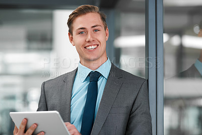 Buy stock photo Cropped portrait of a handsome young businessman standing alone in his office and using a tablet