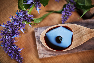 Buy stock photo Shot of a wooden spoon with dark liquid in it surrounded by fresh lavender on a table