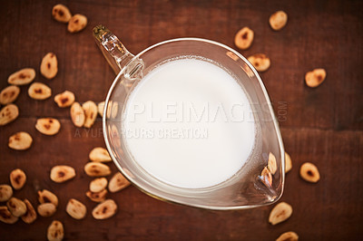 Buy stock photo Shot of a jug of milk surrounded by nuts on a table