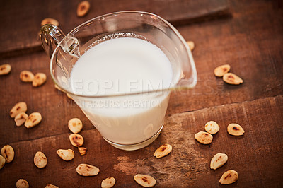 Buy stock photo Shot of a jug of milk surrounded by nuts on a table