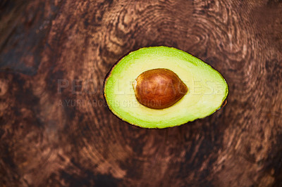 Buy stock photo High angle shot of an avocado cut in half on a wooden table