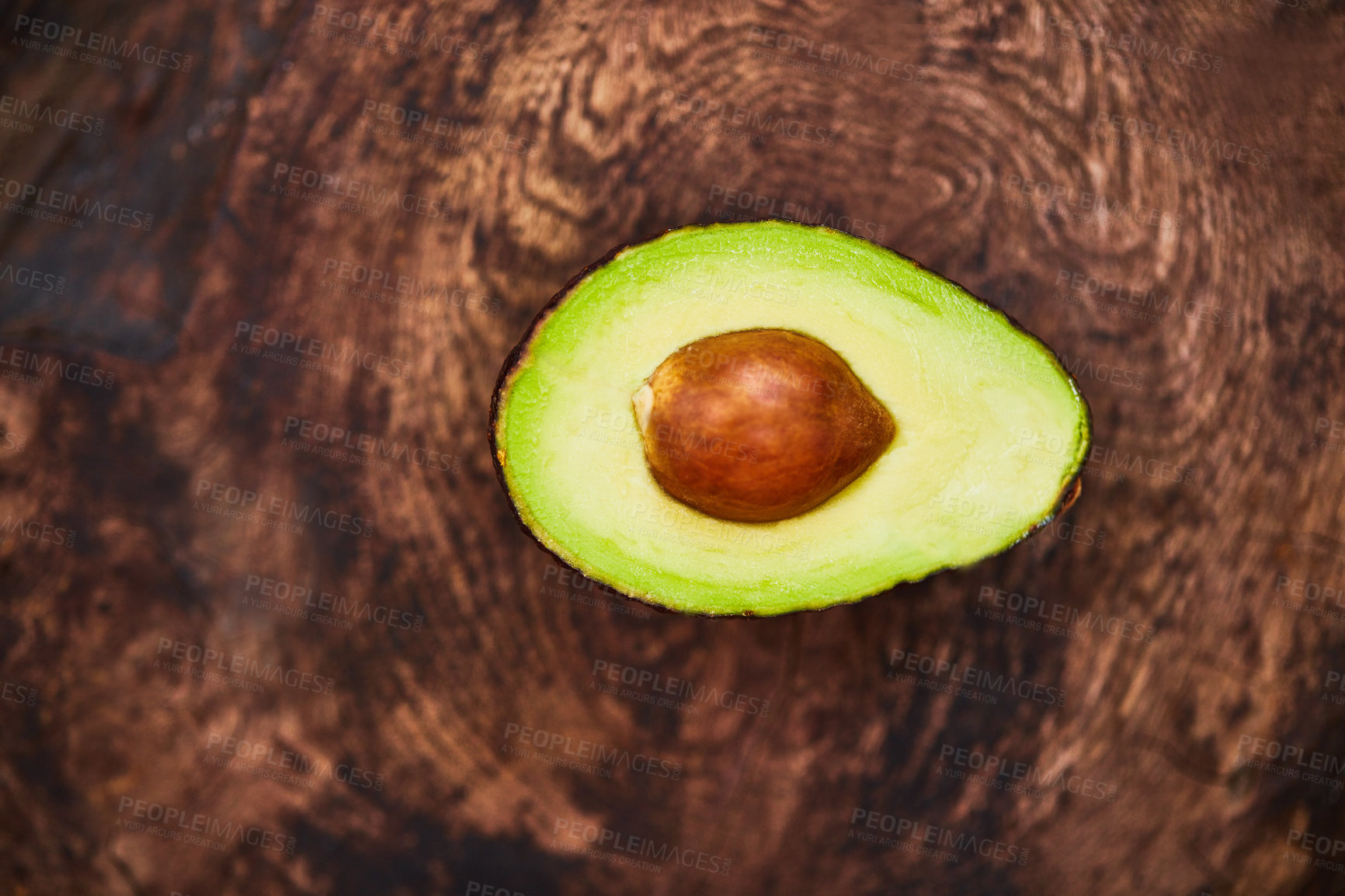 Buy stock photo High angle shot of an avocado cut in half on a wooden table